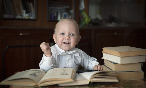 Rapazinho esperto sentado a uma mesa com livros — Fotografia de Stock