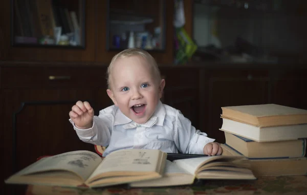 Rapazinho esperto sentado a uma mesa com livros — Fotografia de Stock