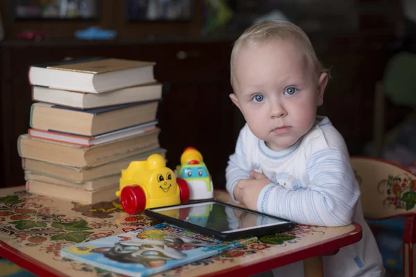 Kleiner kluger Junge sitzt an einem Tisch mit Büchern — Stockfoto