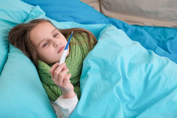 Bir termometre ve ölçü sıcaklık ile yatakta yatan bir hasta bebek