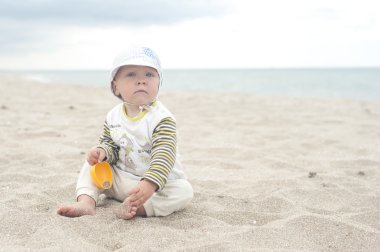 Çocuk kum plaj oturur