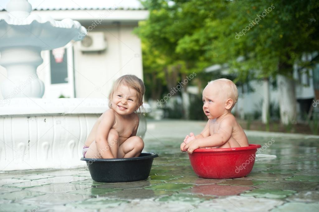 Two children boy and girl sit in basins and talk