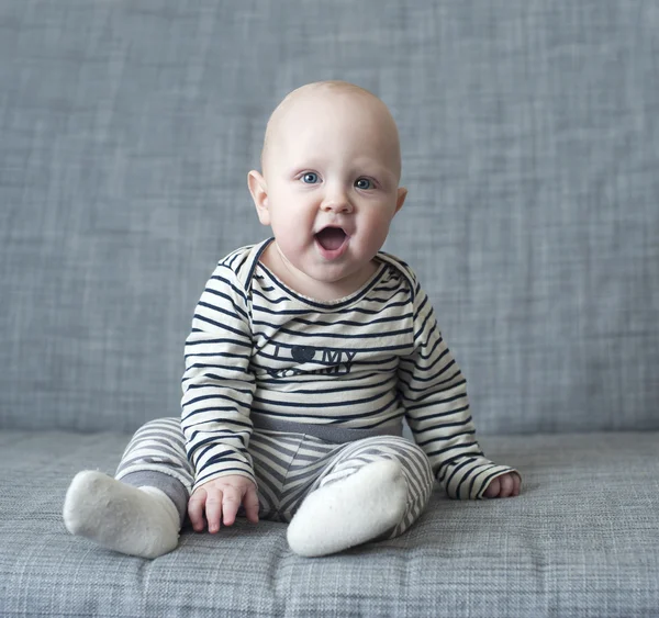 Very surprised kid is sitting on the couch with his mouth open — Stock Photo, Image