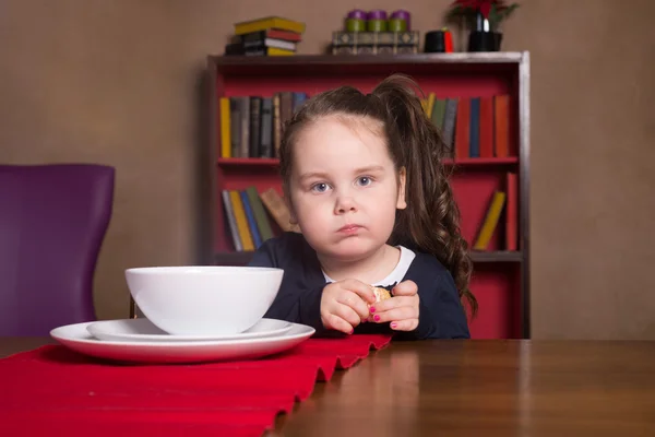 Забавная маленькая девочка сидит за столом — стоковое фото