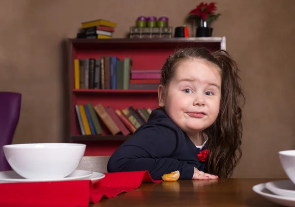 Забавная маленькая девочка сидит за столом — стоковое фото