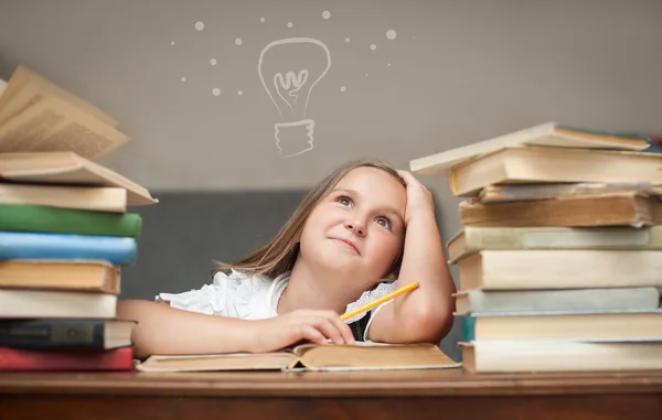 Kız öğrenci rüya kitaplar ile bir masada oturuyor görünüyor