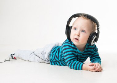 Büyük kulaklıklar yerde yatan ve müzik küçük çocuk