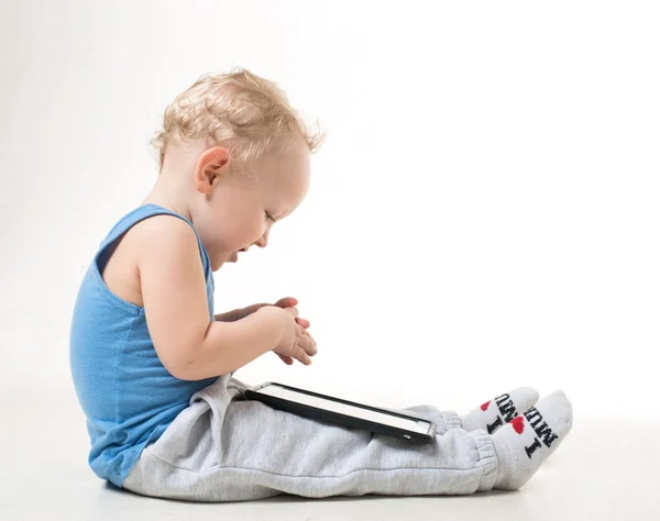 Menino com óculos sentados no chão com um tablet — Fotografia de Stock