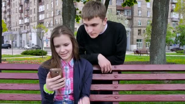 Jongen en meisje met behulp van de mobiele telefoon. Laughing.Outside. — Stockvideo