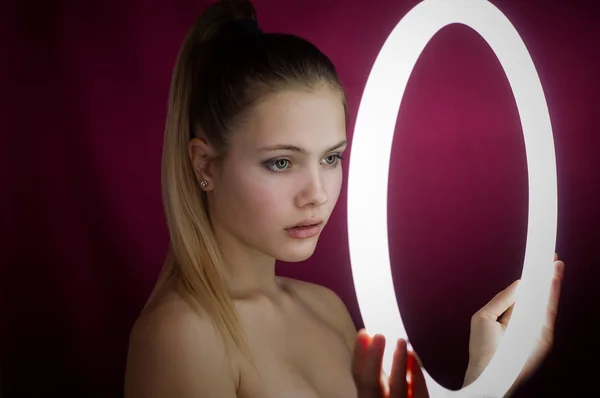 Bir kız parlayan bir dairesel Neon lamba beyaz ışık ile bakar.