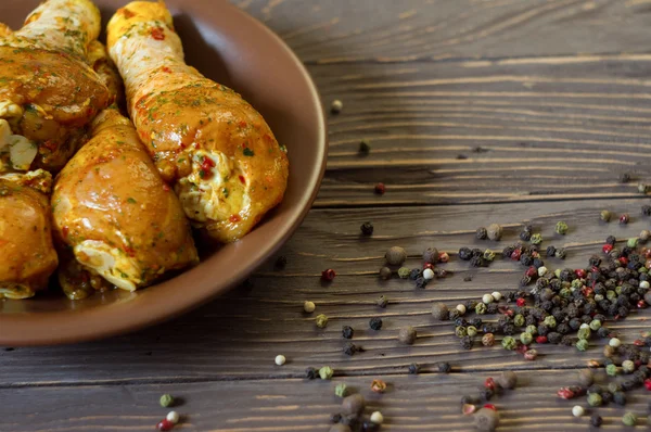 Çiğ tavuk budu baharat yalan bir tepside ile kaplı. Arka plan. Ufalanmış biber renk.