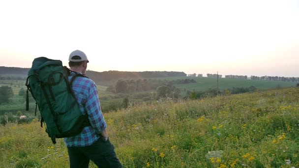 Un hombre barbudo con una mochila caminando en el campo — Vídeo de stock