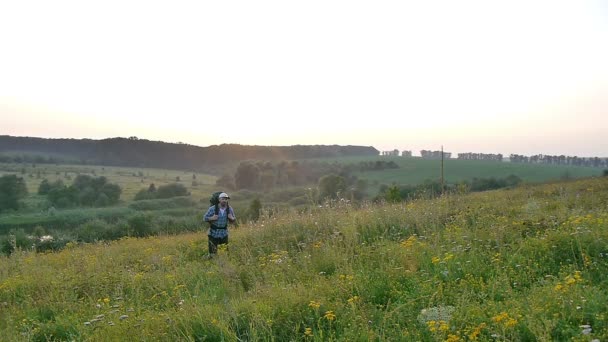 A bearded man with a backpack walking in the field — Stock Video