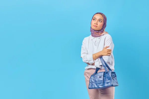 Portrait of sad Asian woman holding bag looking at empty space