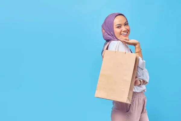 一个心情愉快的女人提着购物袋 在蓝色背景下孤立地向前看的画像 — 图库照片