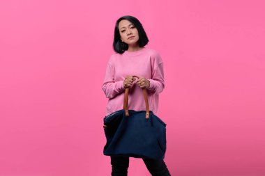 Alışveriş yaparken çanta tutan Asyalı genç kadının yakın plan portresi.