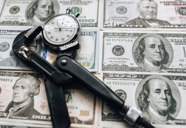Bir ingiliz anahtarına sıkıştırılmış dolar ve saat. Finansal kölelik kavramı, krediler ve bankaya yapılan faiz ödemeleri. Uluslararası Para Fonu.