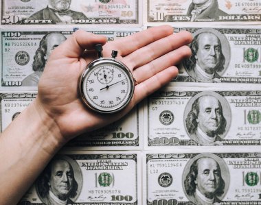 Tefeci, kredi konsepti. Hızlı para zamanı. Bir kadının eli dolar üzerinden gri bir kronometreyi tutuyor..