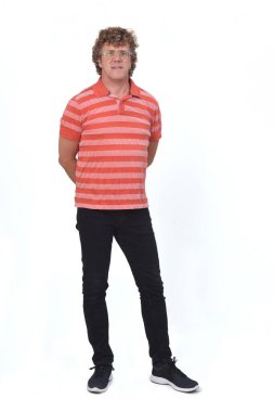 Kıvırcık saçlı, beyaz geçmişi olan, elleri arkada olan bir adamın tam portresi.