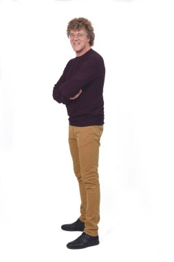 Bir adamın tam portresi, kıvırcık saçlı, beyaz arkaplan, kamera karşısında kollarını kavuşturmuş.