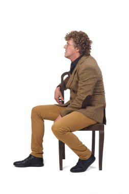 Beyaz arka planda sandalyede oturan ceketli orta yaşlı adamın yan görünüşü, 