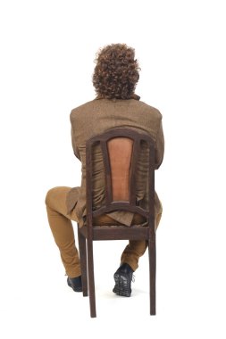 Beyaz arka planda sandalyede oturan, kollarını kavuşturmuş, ceketli orta yaşlı bir adamın dikiz aynası.