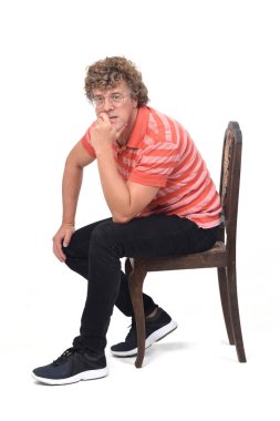 Beyaz arka planda yan yana oturan kıvırcık bir adamın tam portresi.