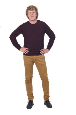 Bir adamın tam portresi, kıvırcık saçlı ve beyaz arkaplan, eller kalçada.