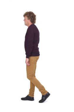 Beyaz arka planda yürüyen kıvırcık saçlı bir adamın yan görünüşü