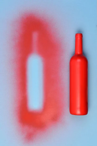 Красная Покрашенная Стеклянная Бутылка Которая Оставляет Негатив Синем Фоне — стоковое фото