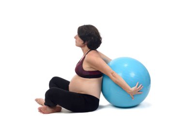 Beyaz arka planda topla egzersiz yapan hamile bir kadın. 