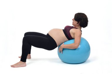 Beyaz arka planda topla egzersiz yapan hamile bir kadın. 