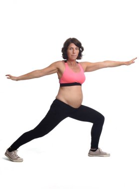 Beyaz arka planda egzersiz yapan hamile bir kadının portresi.