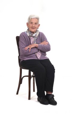 Koltukta oturan yaşlı kadının yan görünüşü arka planda çaprazlanmış.