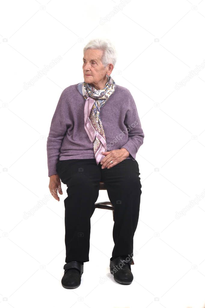 front view of senior woman sitting on chair serious and look side on white background