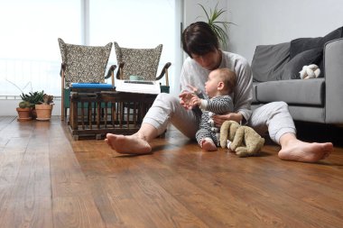 Bir anne bebeğiyle birlikte evin ahşap zemininde