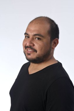 Beyaz arka planda gülümseyen ve kameraya bakan Latin bir adamın portresi.