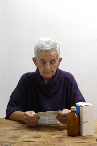 Mulher sênior lendo um folheto de um medicamento — Fotografia de Stock