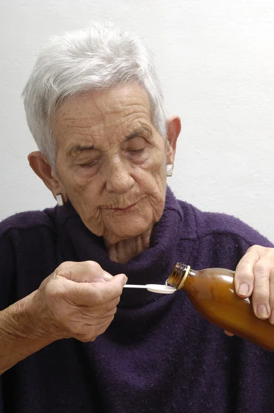 Mujer mayor tomando jarabe — Foto de Stock