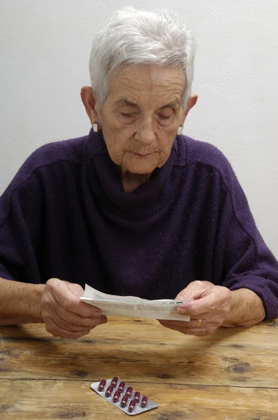 Starsza kobieta czytanie ulotek produktów leczniczych — Zdjęcie stockowe