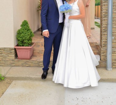 Gelin ve damat birlikte mavi bir çiçek buketi tutuyorlar.