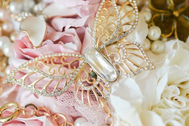 gelin buketi dekorasyonu detaylar; değerli taşlar, altın zincir ve inciler içeren güzel altın kelebek broşu