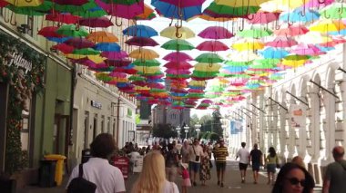 Timisoara, Romanya, 21 Eylül 2025, İnsanlar canlı bir şemsiye ile süslenmiş kentsel caddenin keyfini çıkarıyorlar neşeli bir sonbahar atmosferi yaratıyorlar