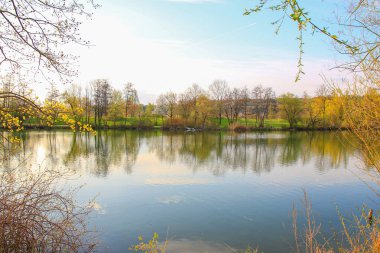 İnsanlar güzel Regensburg ilkbahar doğasında göl kenarındaki manzaralı kırsal bir yolda gezinir ve dinlenir.