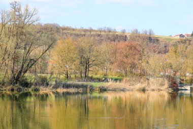 Regenburg, Almanya, 27 Mart 2022: İnsanlar güzel Regensburg ilkbahar doğasında göl kenarındaki manzaralı kırsal bir yolda yürüyüp dinleniyorlar