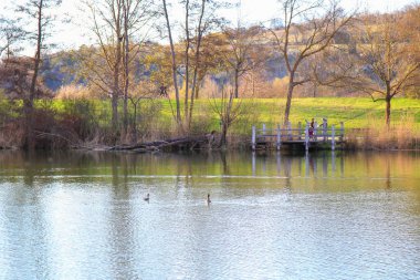Regenburg, Almanya, Nisan 06, 2022: İnsanlar güzel Regensburg ilkbahar doğasında göl kenarındaki manzaralı kırsal bir yolda yürüyüp dinleniyorlar
