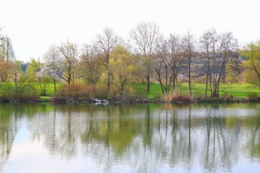 Regenburg, Almanya, 14 Nisan 2022: İnsanlar güzel Regensburg ilkbahar doğasında göl kenarındaki manzaralı kırsal bir yolda yürüyüp dinleniyorlar