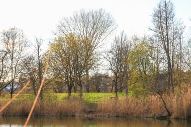 Regenburg, Almanya, Nisan 06, 2022: İnsanlar güzel Regensburg ilkbahar doğasında göl kenarındaki manzaralı kırsal bir yolda yürüyüp dinleniyorlar