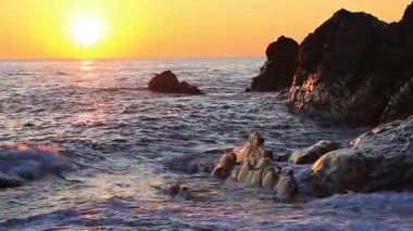 Gün batımında kayalara vuran dalgalar Bogliasco İtalya 'nın güneşinden kırmızıya boyanır..