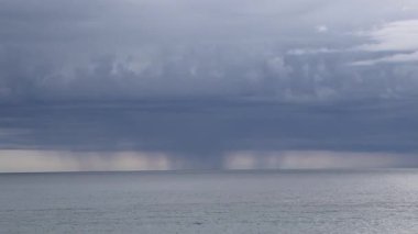 Şiddetli bulutlardan yağan uzak yağmur, sakin okyanus ufkunda Bogliasco İtalya 'ya düşüyor.